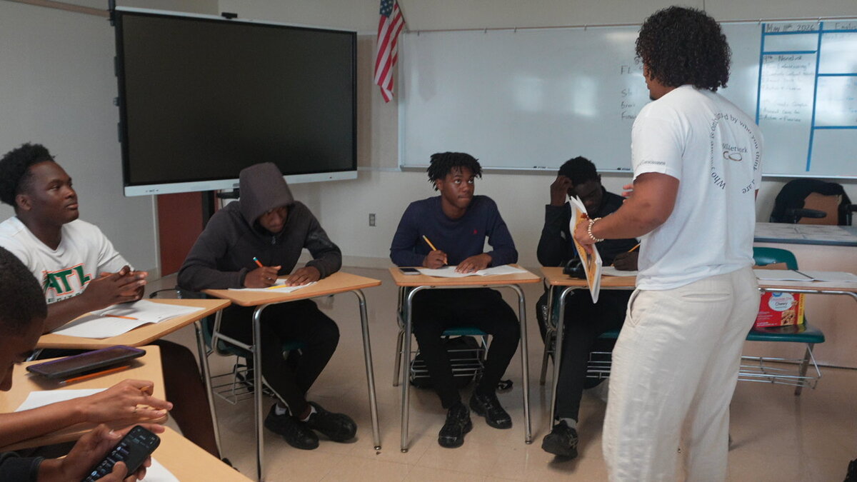 Student-athletes writing in a classroom with a facilitator