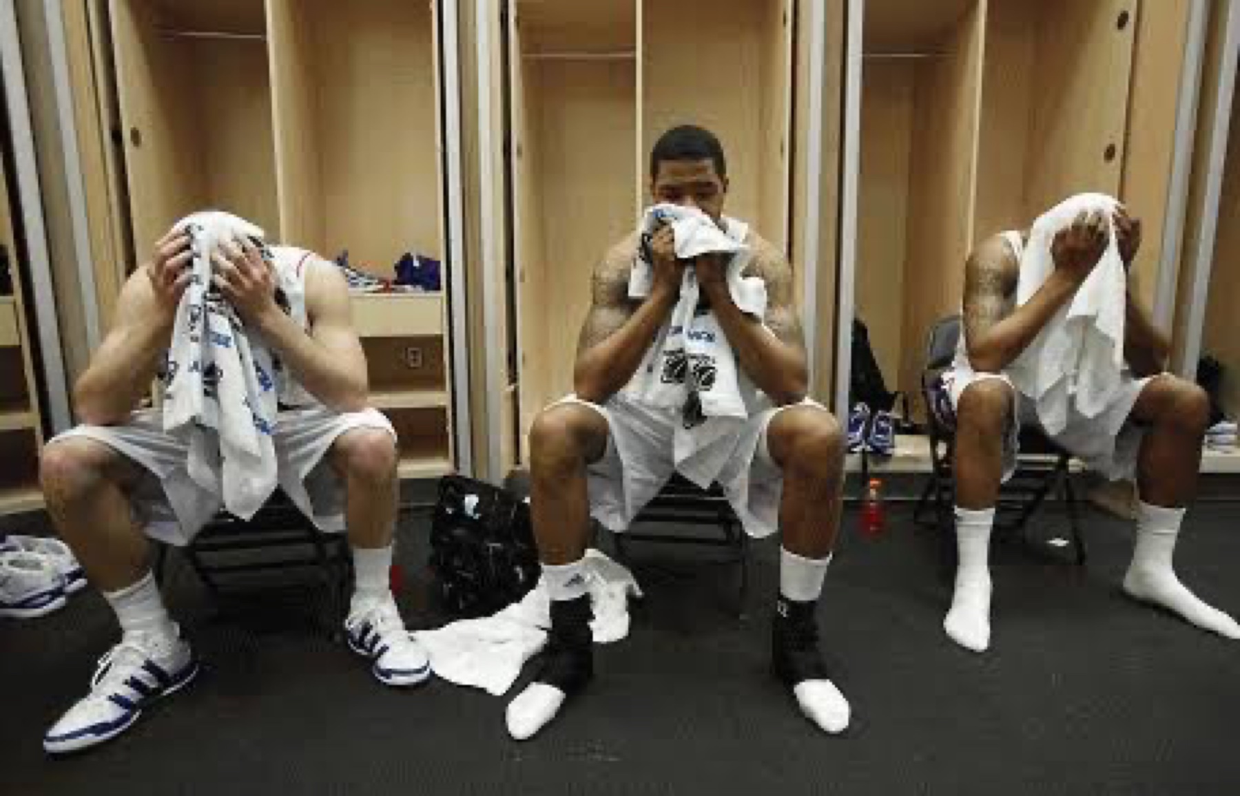 Teammates sitting with towels over their faces after a hard practice