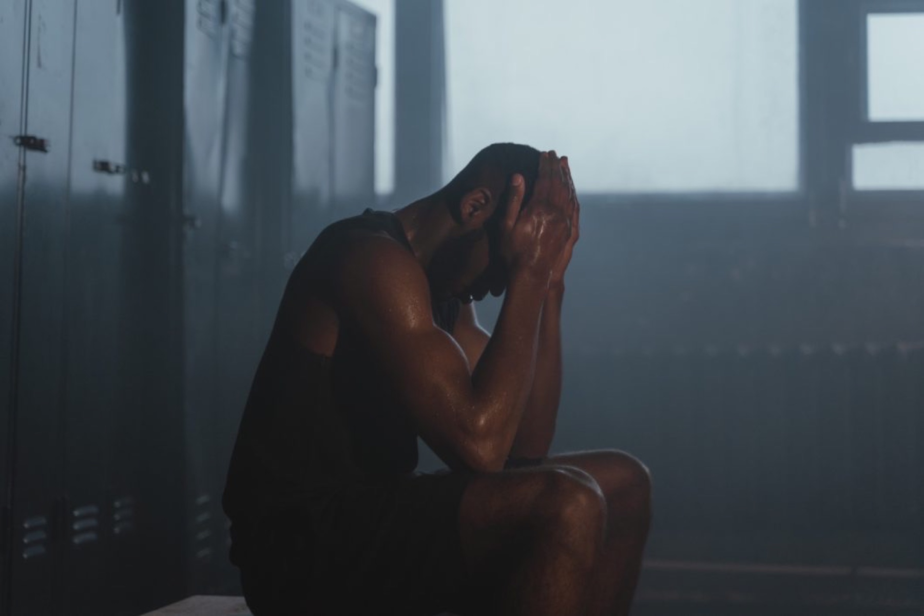 A young man alone with his head in his hands